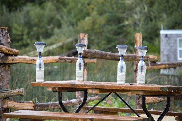 Solar Lighting - four water bottles sitting on top of a picnic table