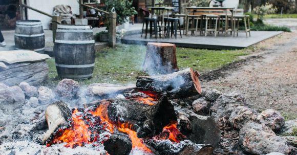 Build A Fire Pit - Stone fire pit with burning firewood placed on courtyard of residential building with chairs and table on terrace in countryside
