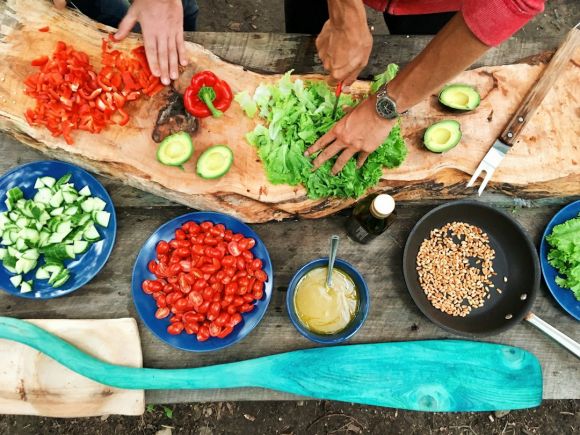 Outdoor Kitchen - person slicing green vegetable in front of round ceramic plates with assorted sliced vegetables during daytime